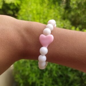 A white bracelet with a pink heart